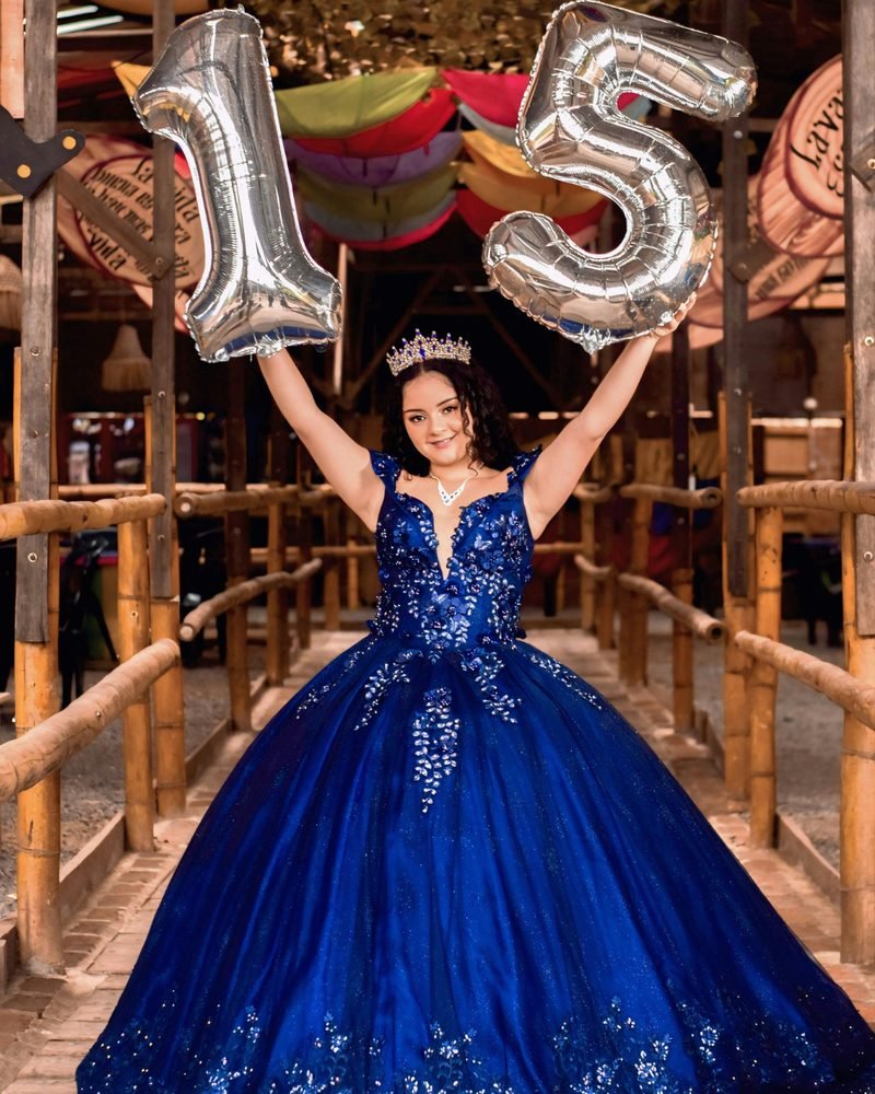 A quinceañera holding giant 15 balloons